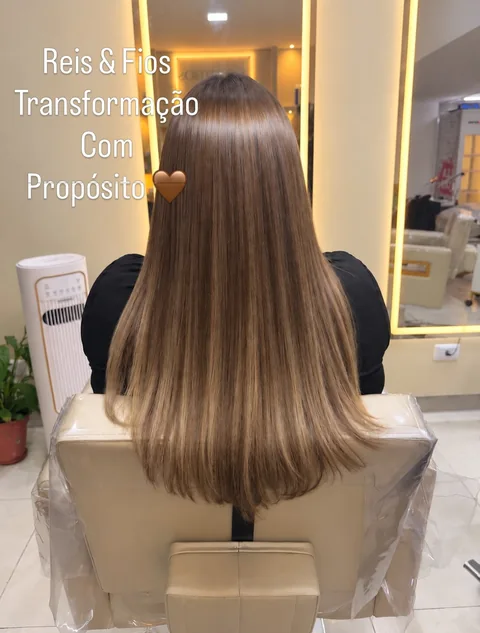 Cabelo castanho claro comprido de costas diante do espelho do salão.