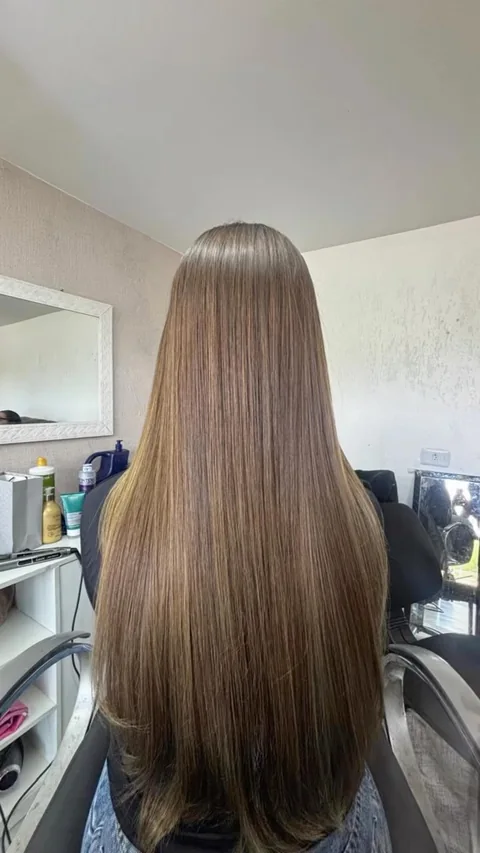 Cabelo castanho liso fotografado de costas no salão.